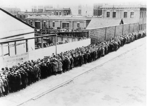 Long line of unemployed and homeless men wait outside to get free dinner at the municipal lodging house during the Great Depression in New York