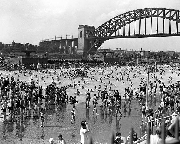 New Yorkers seek relief from heat at Astoria Park Swimming Pool. The American flag and New York City flag frame the Astoria Pool where thousands