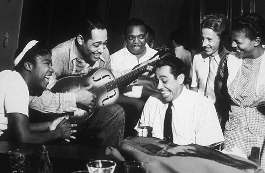 American composer and bandleader Duke Ellington plays guitar and Cab Calloway plays piano during a jam session at a private party hosted by Hearst