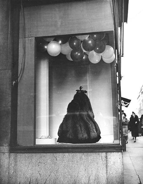 Balloons hanging in the window of H Jaeckel and Sons on Fifth Avenue and 45th Street attract the attention of passersby who stop to look at the