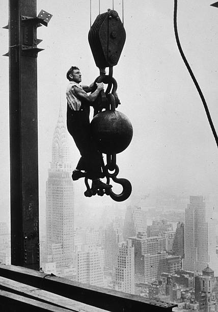Construction worker stands on crane pulley counterweight during the construction of the Empire State Building New York New York. Mid to late 1930.