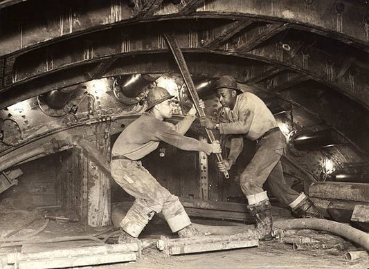 Construction workers or sandhogs working nearly seventy feet below the East River New York tightening the bolts of the cast iron lining of the