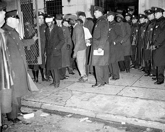 One the way to line-up at Police Headquarters. Some of the 120 prisoners taken during Harlem's night of terror are loaded into patrol wagon in front