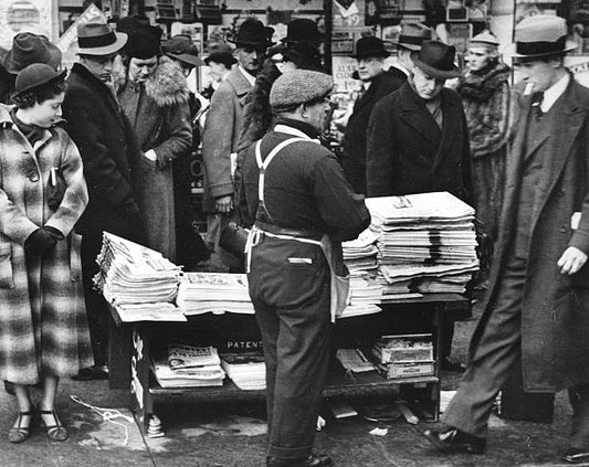 Pedestrians gather around a newsstand on 5th Avenue and 42nd Street to avidly scan all the latest headlines New York New York early to mid 20th