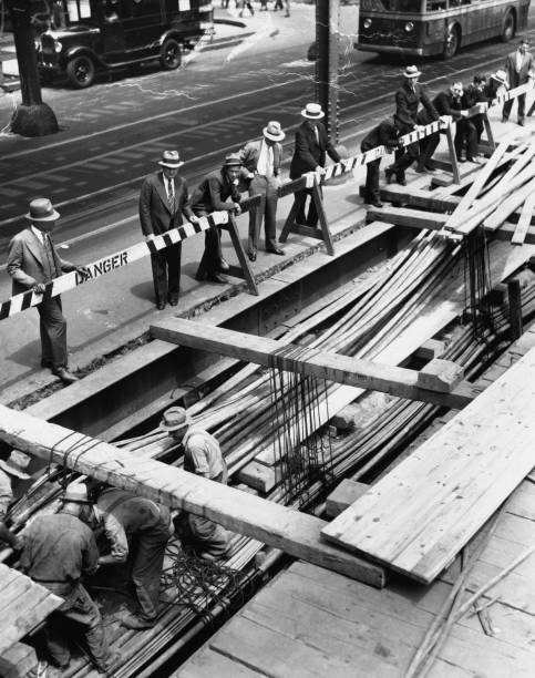 Pedestrians lean on the barriers during excavation of 6th Avenue for the Sixth Avenue Line of the New York subway in the Manhattan borough of New