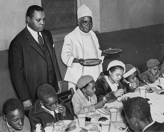 Police Lieutenant Samuel J. Battle watches his little guests having their Thanksgiving dinners at Mother Zion Church in Harlem at 151 West 136th St.