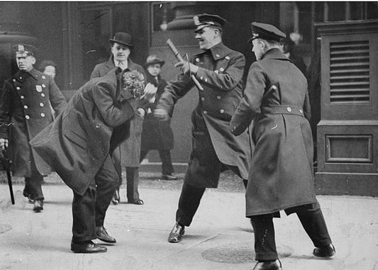Police officer striking a communist protester outside of City Hall.
