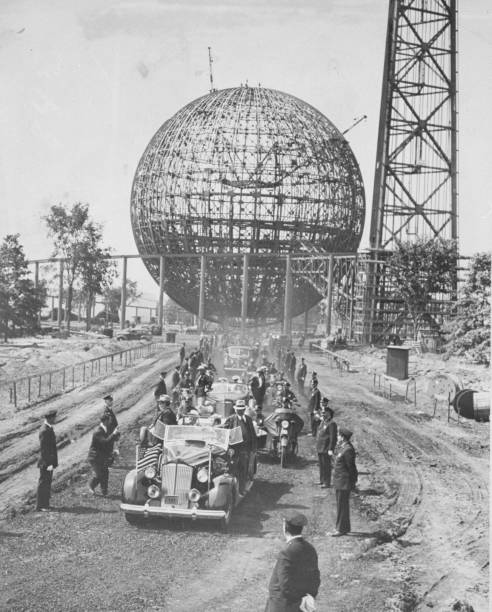 President Franklin D. Roosevelt rides in procession with the perisphere in the background at the World's Fair.