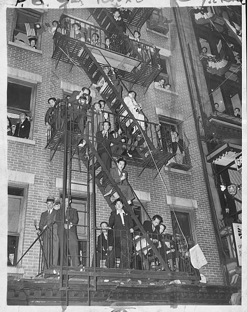 Residents of New York's Chinatown clamber onto their fire escapes to gain a view of the local 'Rice Bowl' party. The party is one of 2000 or so held