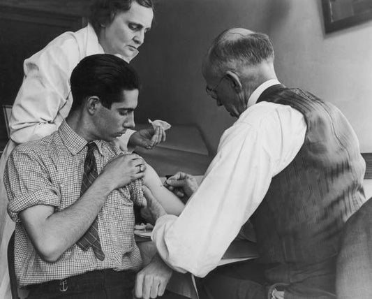 Teenage boy is vaccinated against smallpox by a school doctor and a county health nurse Gasport New York 15th March 1938.