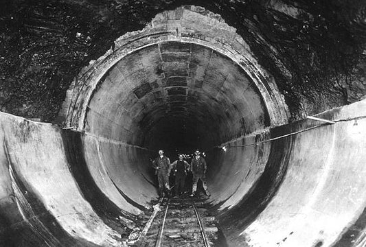 Three workmen standing in one of the tunnels of the New York city water system.