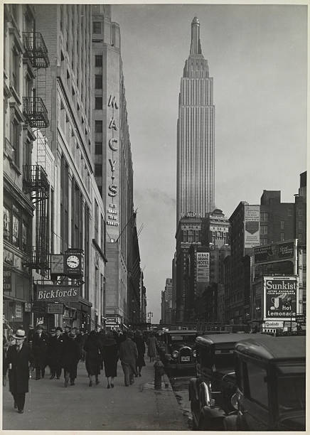 View from Penn Station on 34th Street facing east. Signs on buildings for Macy's Bickford's Herald Square Hotel and the McAlpin Hotel are visible.