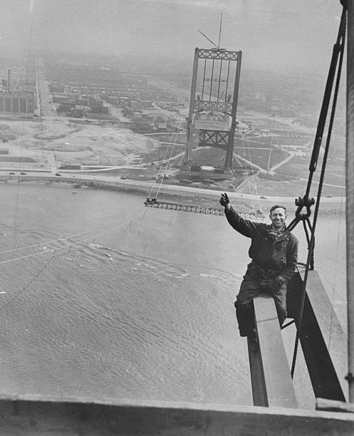 Workman Sam Genier waves from girder on pier 315-feet above Ward's Island during construction of the Triboro Bridge. The bridge's other pier stands