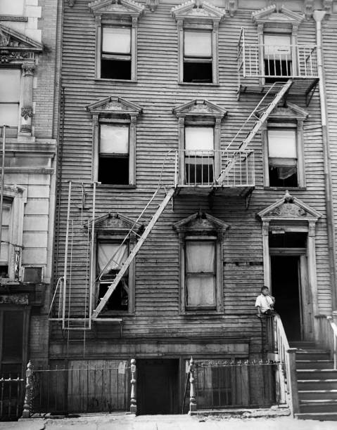 Young African-American boy waits at the bottom of his building in a slum of New York in November 1937 United States.